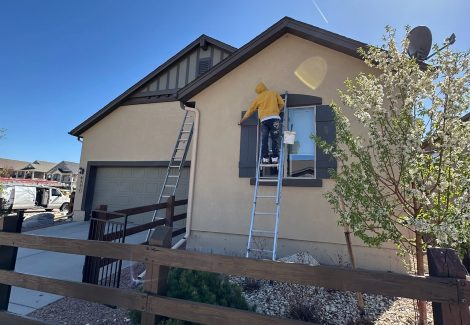 painter on ladder painting a stucco house