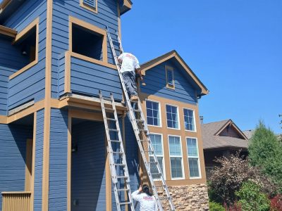 painters with ladders working on outside of home