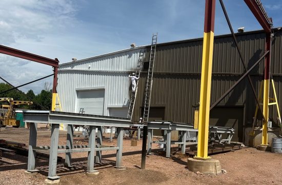 painter on ladder against industrial building