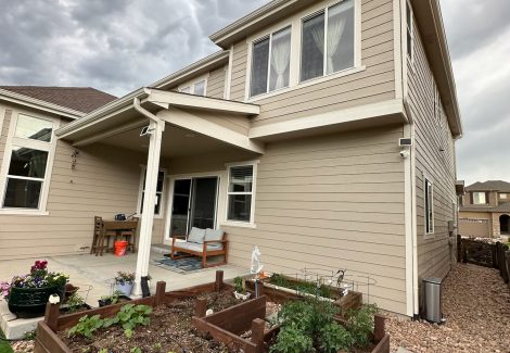 rear corner of house with covered patio and raised bed garden