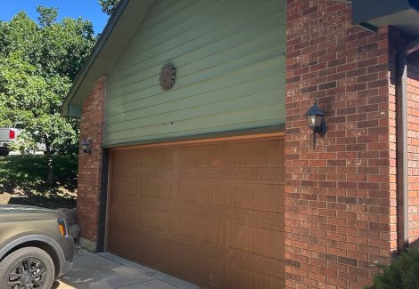 house with green painted siding and wooden garage door