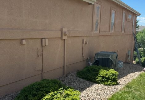 side of painted stucco house with plastic sheeting on windows