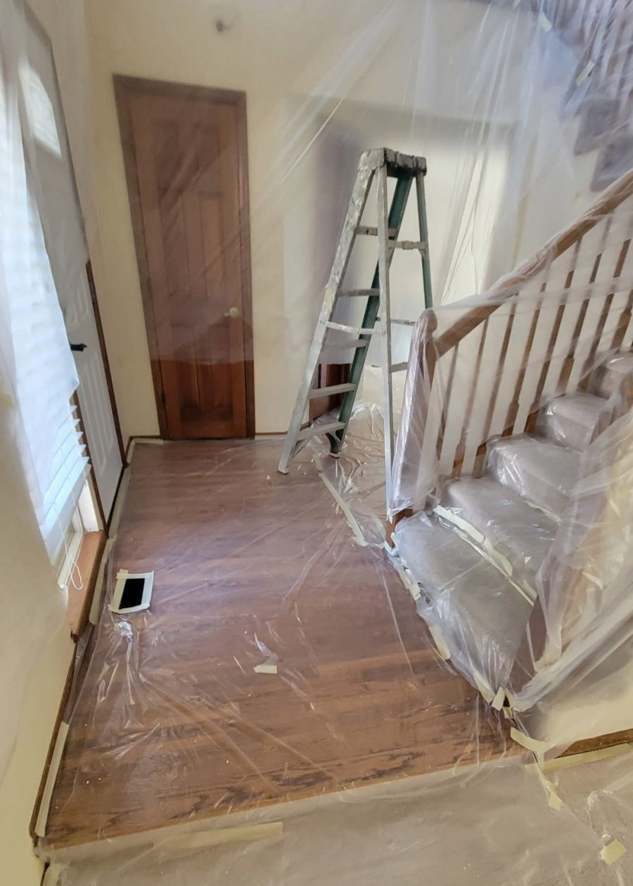staircase and foyer covered in plastic sheeting for painting