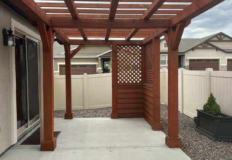 stained wooden pergola with patio behind home