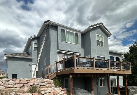 review view of house with stucco siding and wooden deck