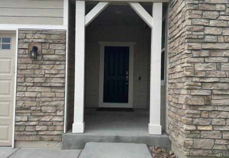 front door and covered stoop of house with stone siding