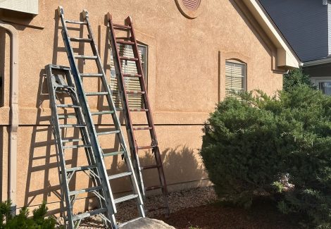 ladders leaning against painted stucco house