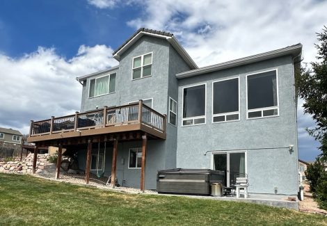 review view of house with stucco siding and wooden deck