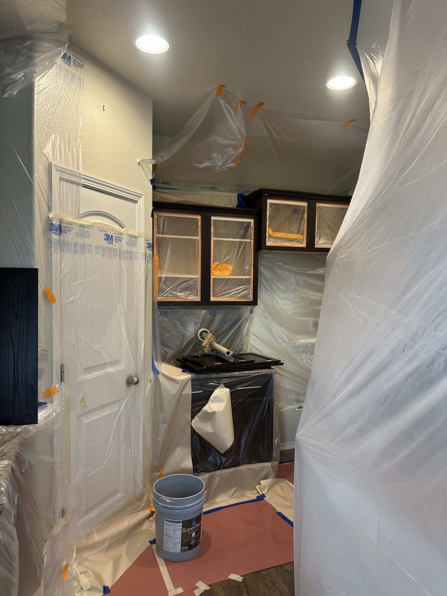 kitchen cabinets with doors removed for painting, and protective sheeting over lower counters and appliances Preview Image 3