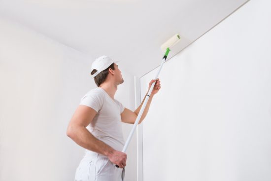 painter rolling paint on a ceiling