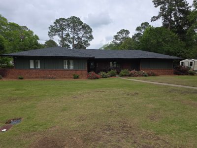 brick house with dark green painted siding and accents