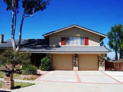 Two story tan house with red shutters.