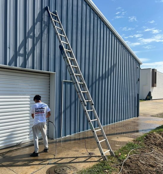 painter pressure washing a commercial building