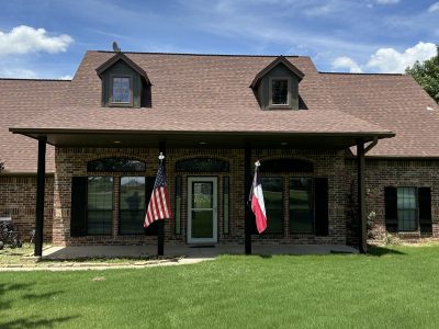 front exterior of house with covered porch and American and Texas flags