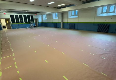 wide angle view of school gym with floor covered for painting project