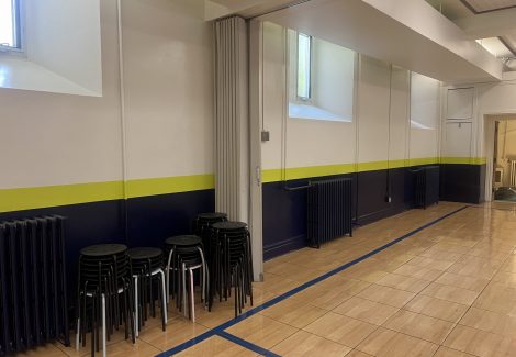 chairs stacked along wall in school gym in front of painted wall