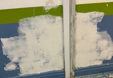 blue gymnasium wall being primed for repainting