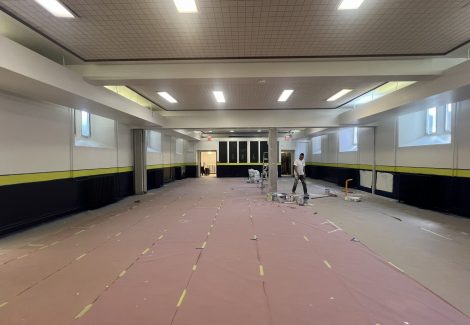 painter walking through school gym with floors covered for repainting project