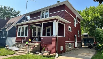 street view of home with dark red painted wood siding and white trim