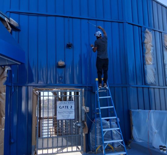 painter on ladder against blue painted building