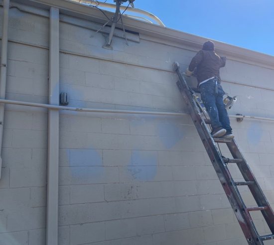 painter on ladder against commercial building wall