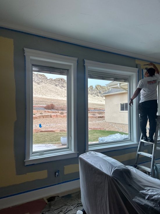 painter working on wall around windows