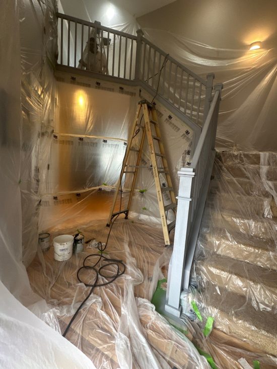 home staircase with plastic sheeting during repaint