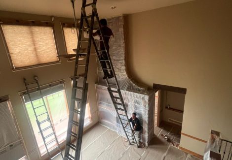 painter on tall ladder in room with vaulted ceiling