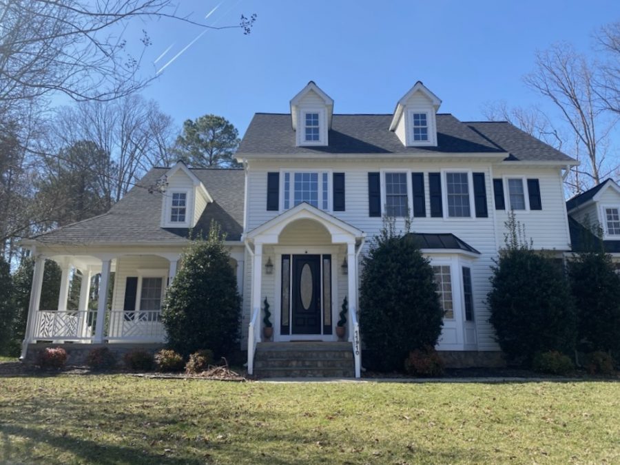 front exterior of white house with black shutters and door