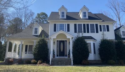 front exterior of white house with black shutters and door