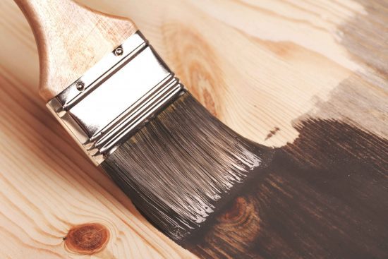 brush applying paint to wood