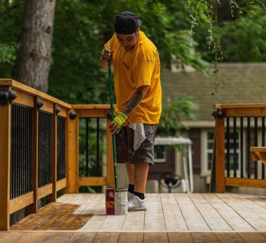 CertaPro Crew Member applying a stain to a deck