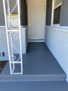 Concrete porch painted medium gray with white wrought iron railing.