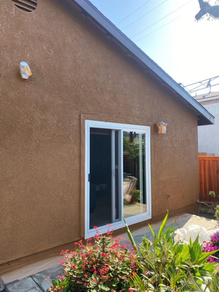 Side view of stucco home showing white trim against dark ochre stucco. Preview Image 3