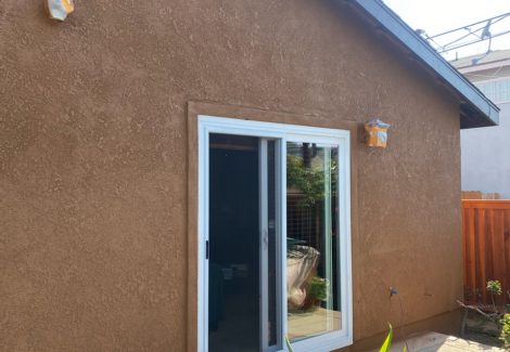 Side view of stucco home showing white trim against dark ochre stucco.