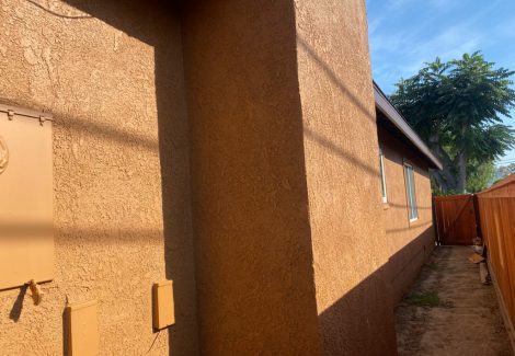 Side of house repainted in a dark tan over stucco.