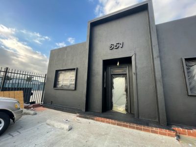 Dark gray building after being painted with a spray rig.