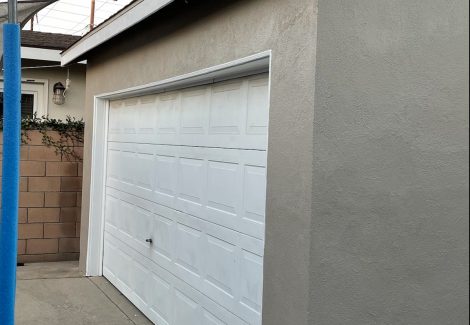 gray stucco garage with white doors.
