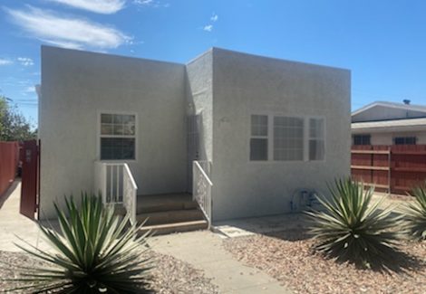 off white stucco home with a flat roof.