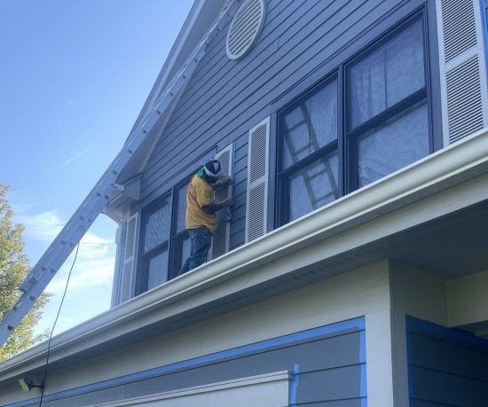 person on house roof painting