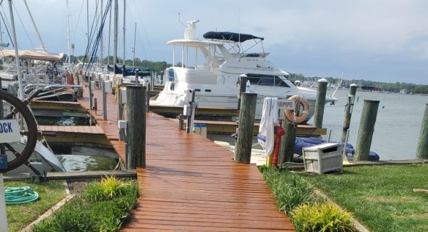 finished painted wooden dock leading to maryland harbor with white yachts