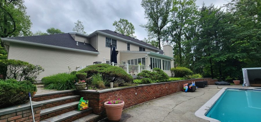 rear exterior of house with painted vinyl siding and brick half wall