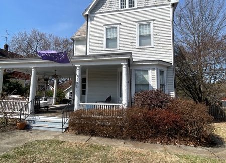front of house with worn white siding