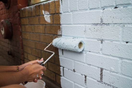 person painting a brick wall white