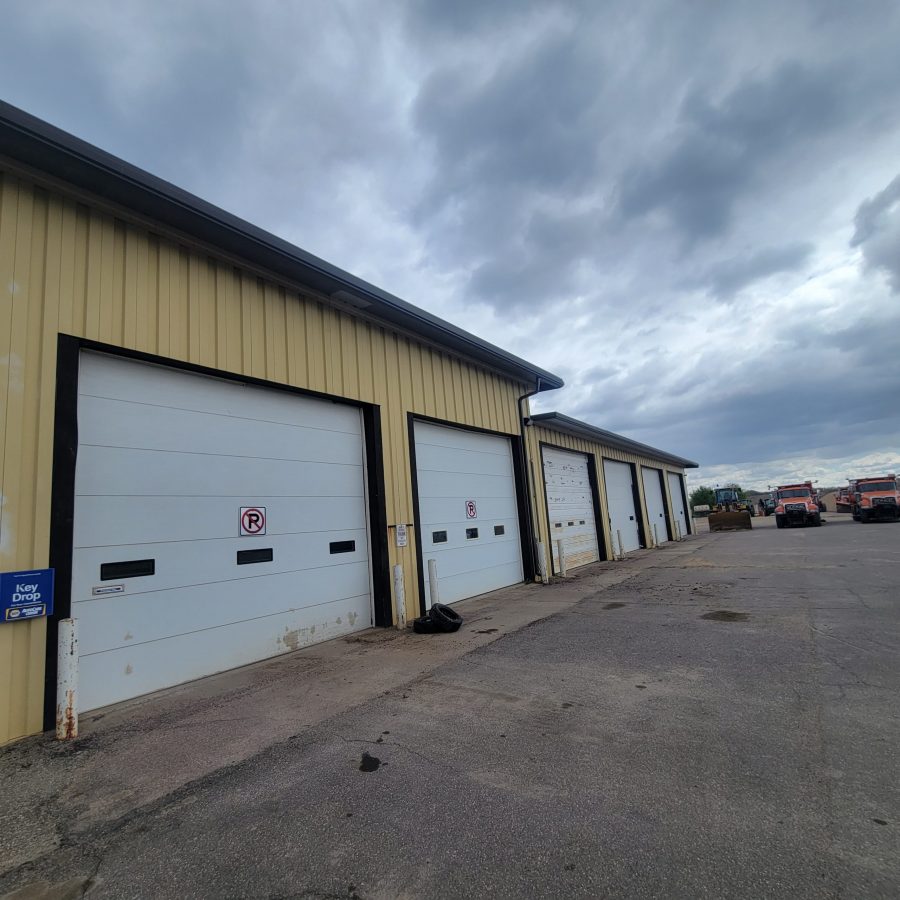 greyish yellow paint job done on commercial building with large white garage doors underneath gloomy weather in Le Center, Minnesota Preview Image 3