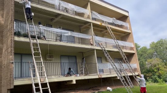 certapro painters using ladders to access balconies and paint patio walls at green circle drive condos during exterior painting