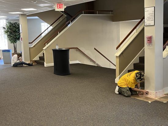 CertaPro Painters installing floor trim on lobby walls of Westgate Church Plymouth