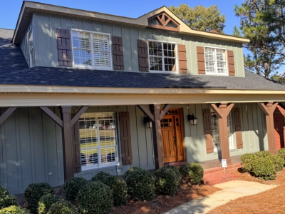 house with green painted siding and rust colored accents and posts