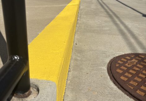 sidewalk with yellow safety paint on curb