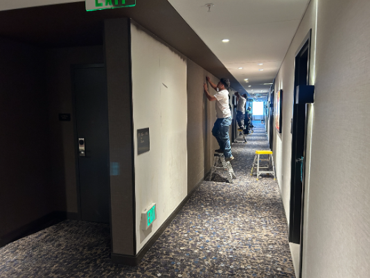 man applying wallpaper in hotel hallway Preview Image 1